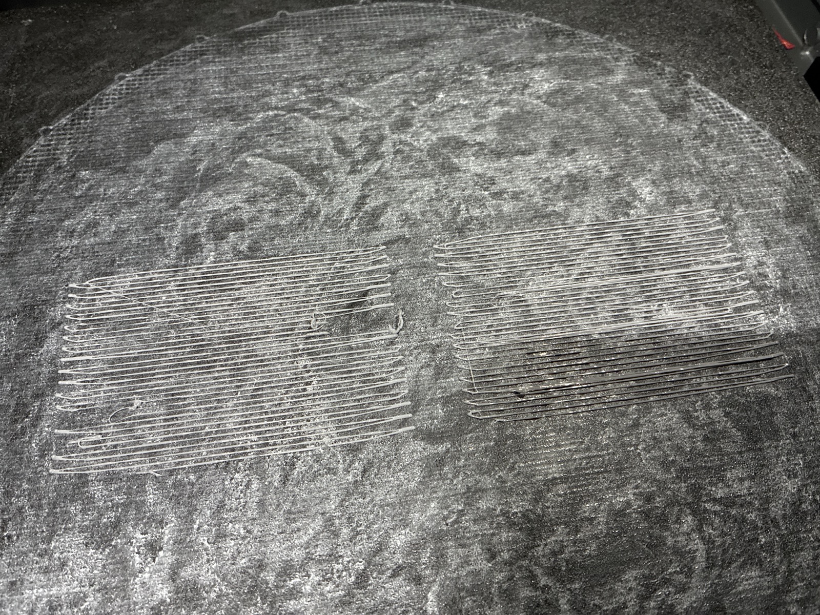 Two rectangular stencil coupon patches on the build plate, both come out as loose unwelded strands, part of one patch dark and broken
