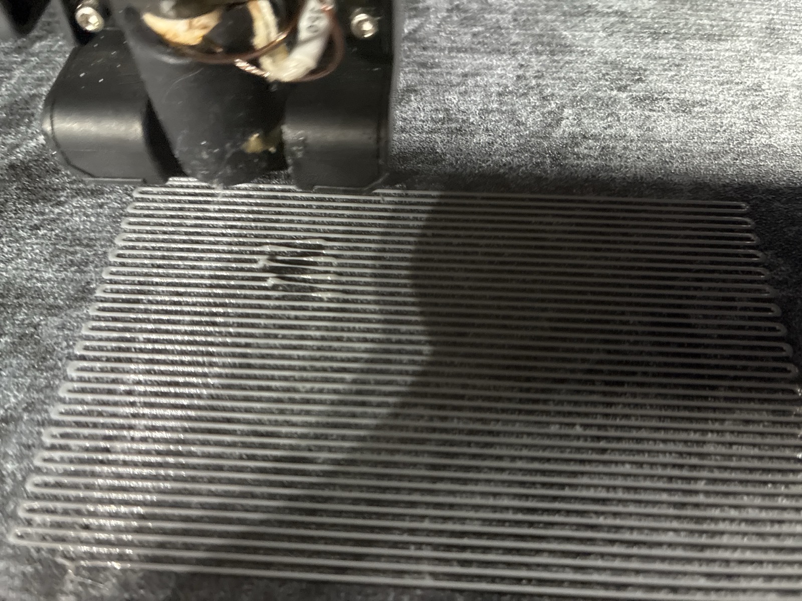 First-layer raster with visibly interrupted extrusion: several lines stop and restart, leaving gaps in an otherwise even field